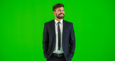 Man in suit standing in front of a green screen backdrop